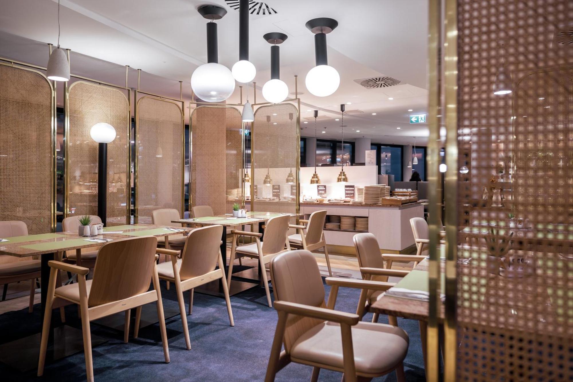 斯维诺乌伊希切丽笙布鲁酒店 外观 照片 The photo shows a modern restaurant interior. There are wooden tables and chairs arranged neatly. The atmosphere appears warm and inviting, with soft lighting provided by round pendant lamps hanging from the ceiling. Partitions made of woven material