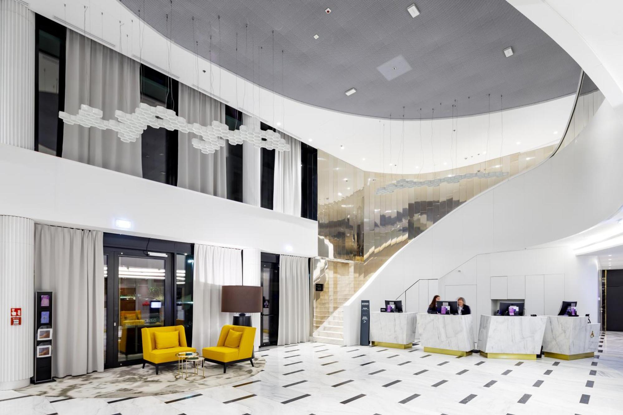 斯维诺乌伊希切丽笙布鲁酒店 外观 照片 The photo shows a modern interior space, likely a hotel or a lobby area. It features a spacious, open design with high ceilings and a stylish staircase that leads to an upper level. The walls are mostly white, with large windows allowing natural ligh