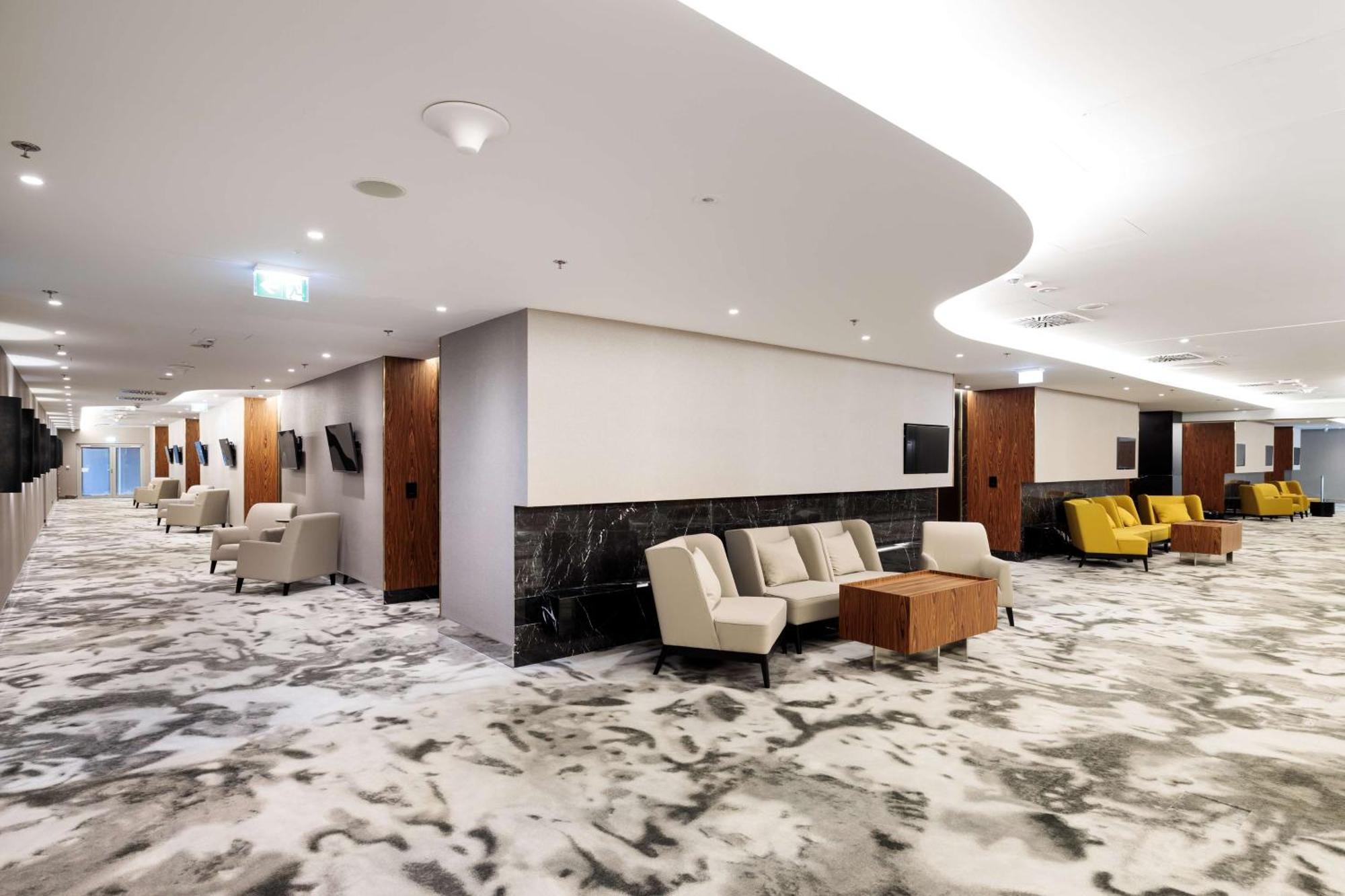 斯维诺乌伊希切丽笙布鲁酒店 外观 照片 The photo shows a modern interior space, likely a lobby or lounge area. The flooring features a patterned carpet, and the walls are neutral in color, creating a calm ambiance. There are comfortable seating arrangements, including a group of beige cha