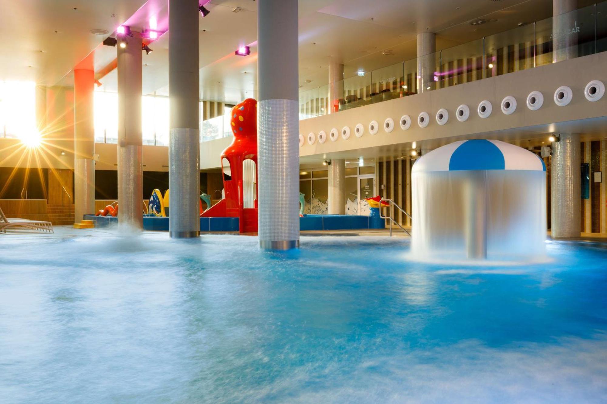 斯维诺乌伊希切丽笙布鲁酒店 外观 照片 The photo shows an indoor water park or pool area. There is a large body of water with playful features, including a water slide shaped like a red bear and a smaller structure with a blue and white canopy. The lighting is bright, suggesting a sunny a
