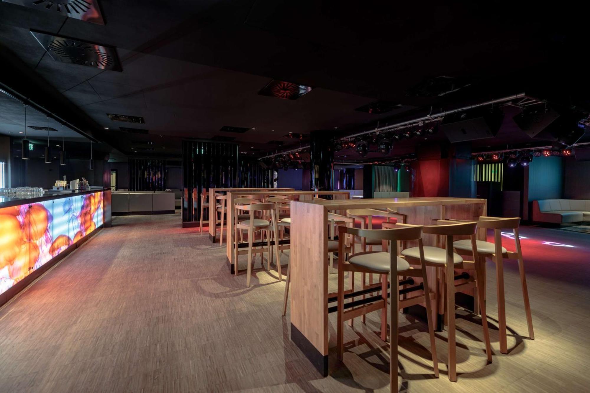 斯维诺乌伊希切丽笙布鲁酒店 外观 照片 The photo shows an interior space that appears to be a bar or lounge. It features a modern design with a dark color scheme. There are several wooden high-top tables with matching stools arranged in the area. In the background, there is a bar counter,