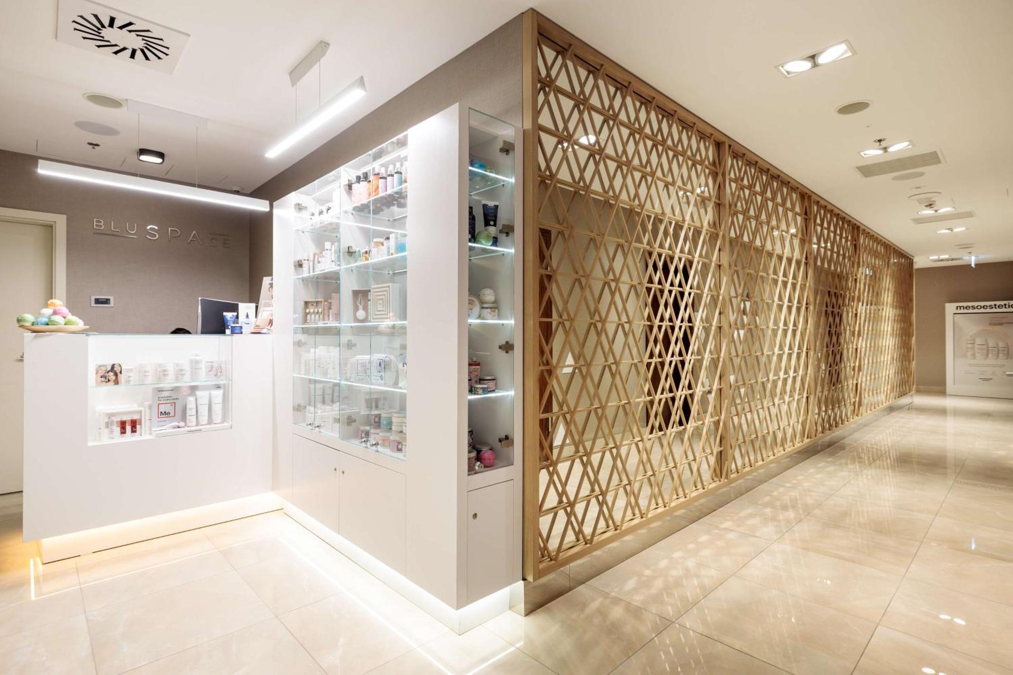 斯维诺乌伊希切丽笙布鲁酒店 外观 照片 The photo shows a modern interior, likely from a spa or skincare clinic. On the left, there is a reception area with a sleek white counter and an illuminated display showcasing various skincare products. The wall behind the reception features a glass