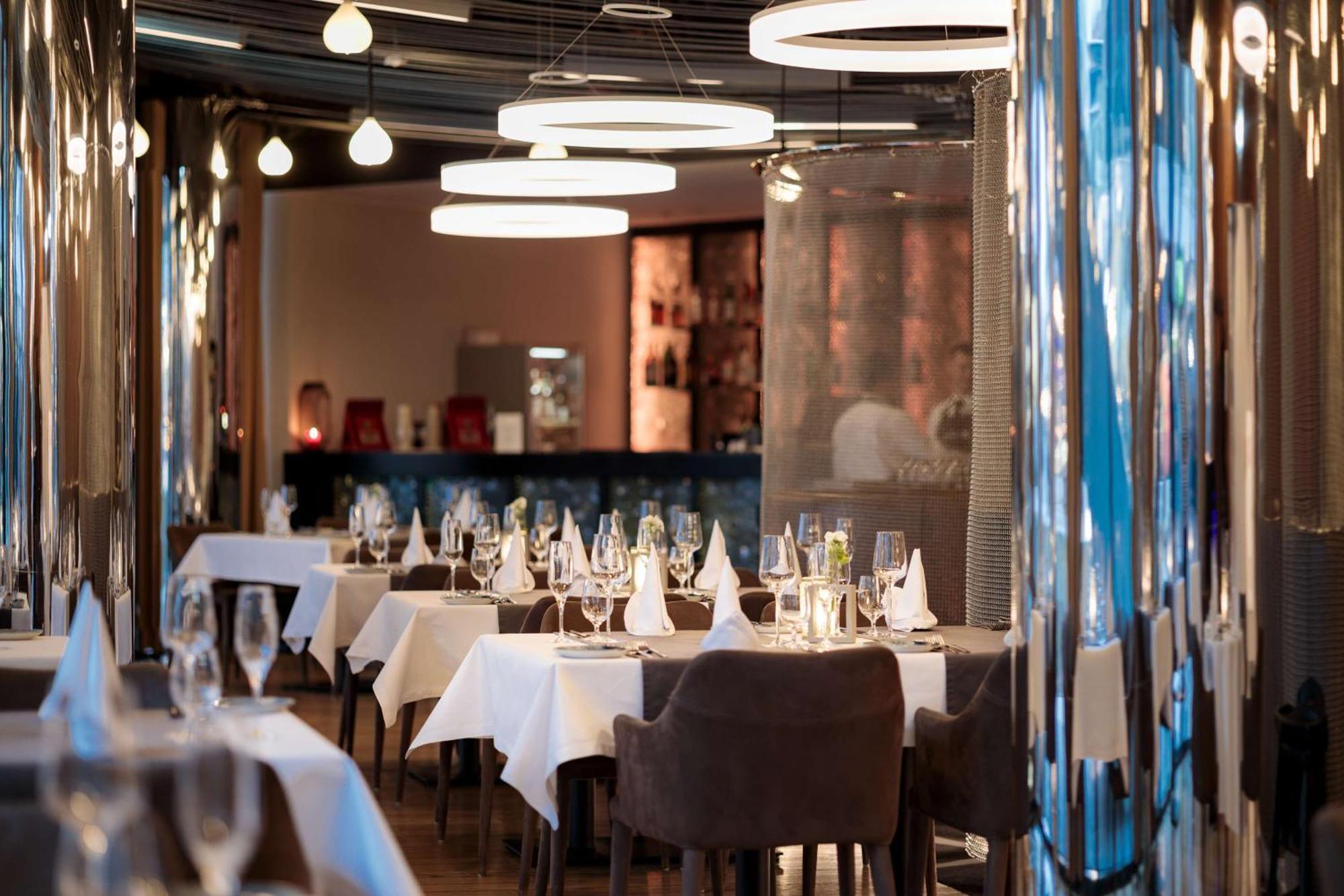 斯维诺乌伊希切丽笙布鲁酒店 外观 照片 The photo depicts an elegant restaurant interior. There are several tables covered with white tablecloths, each set with glassware and napkins, suggesting a fine dining experience. The chairs are upholstered, providing a comfortable seating arrangeme