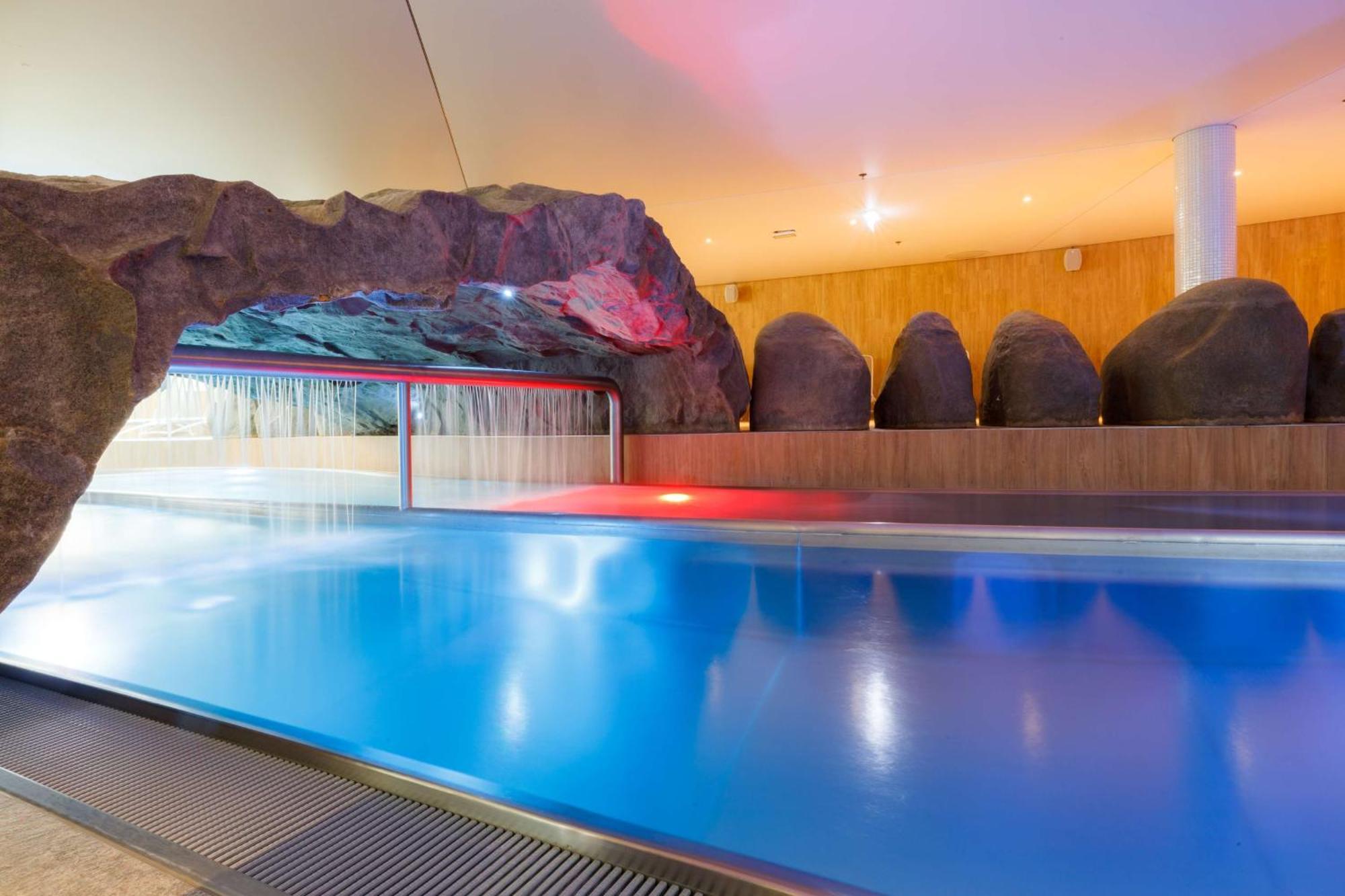 斯维诺乌伊希切丽笙布鲁酒店 外观 照片 The photo shows a serene indoor swimming pool area. The pool has clear blue water, and there is a distinctive rock formation that resembles a cave on one side. Soft lighting enhances the atmosphere, casting a gentle glow across the space. In the back