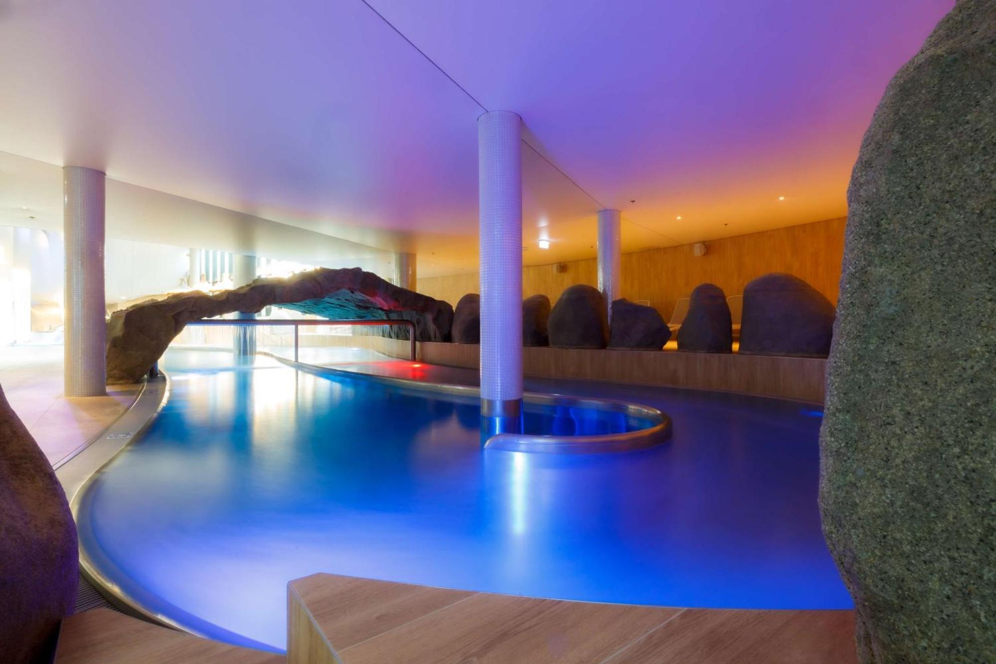 斯维诺乌伊希切丽笙布鲁酒店 外观 照片 The photo showcases an elegant indoor swimming pool area. The pool has a flowing, organic shape and is illuminated with soft blue and purple lighting, creating a calming ambiance. Surrounding the pool are smooth, natural-looking stones and wooden ele