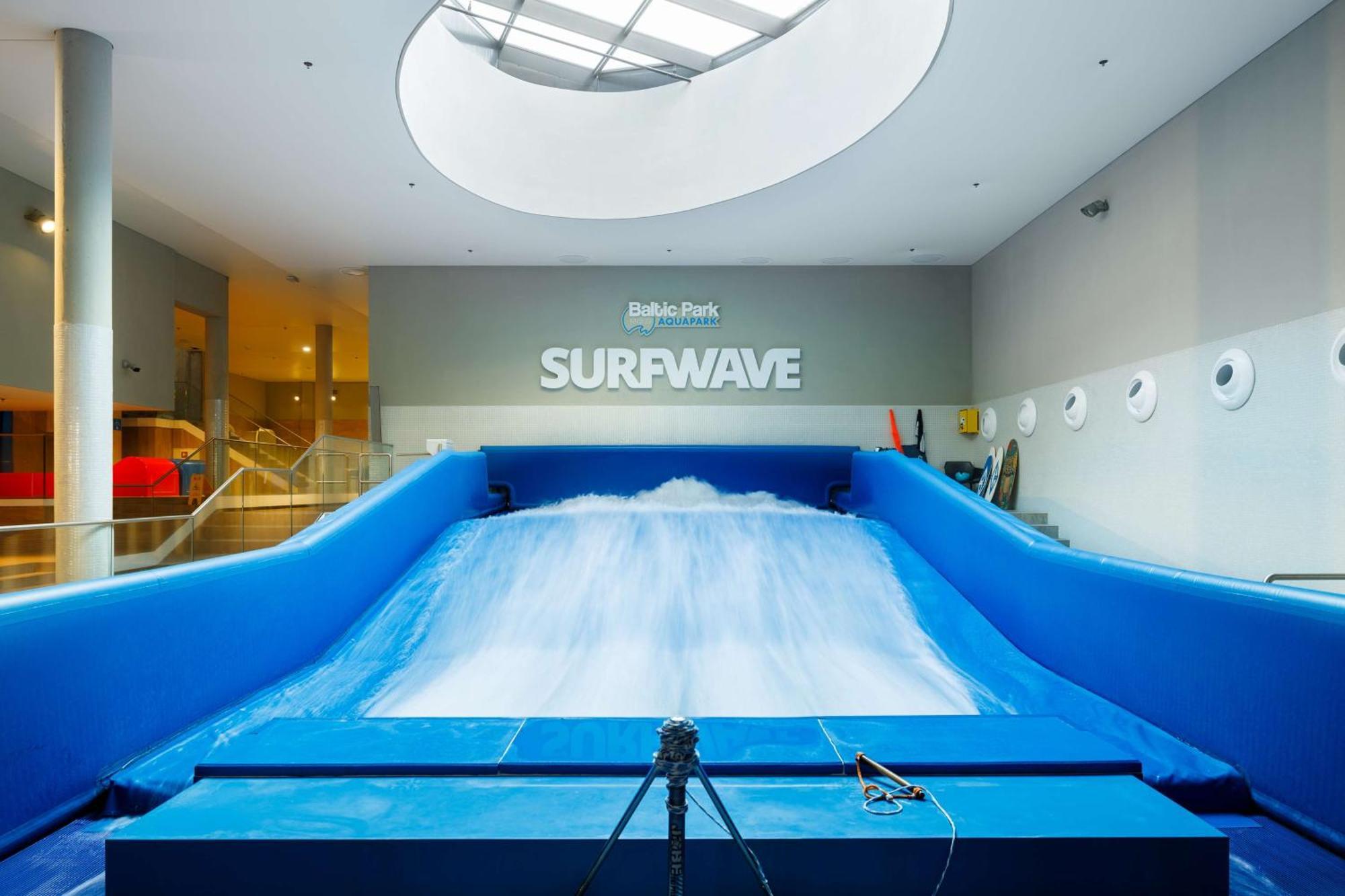 斯维诺乌伊希切丽笙布鲁酒店 外观 照片 The photo shows an indoor surfing attraction called "Surfwave." It features a large blue ramp with water flowing down it, creating a wave-like effect for surfing. Above the ramp, there is a sign that says "SURFWAVE." The area appears well-lit and mod